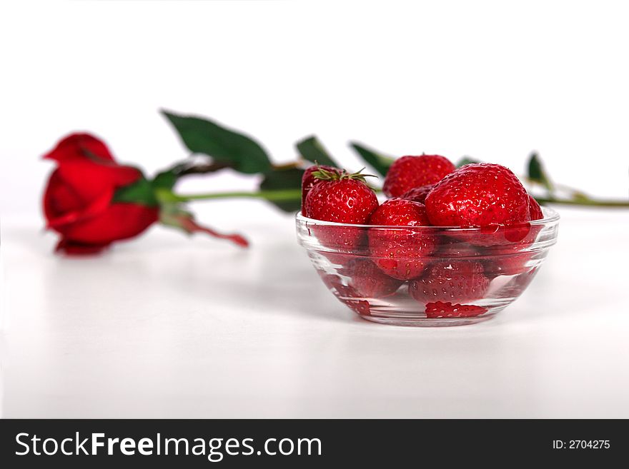 A bowl of fresh strawberries and a single red rose. A bowl of fresh strawberries and a single red rose.