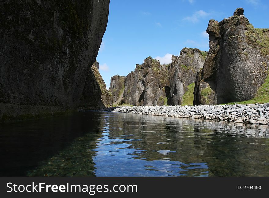 Magnificent scenic from inside a river canyon in southern Iceland, cliffs on all sides, and blue sky above