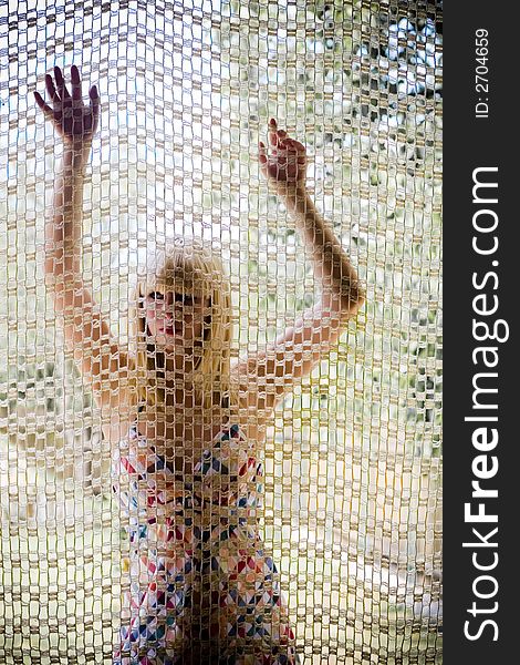 Young blonde girl behind a net