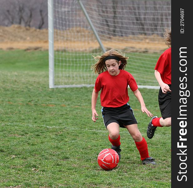 Girl kicking ball at soccer field during a game. Girl kicking ball at soccer field during a game.