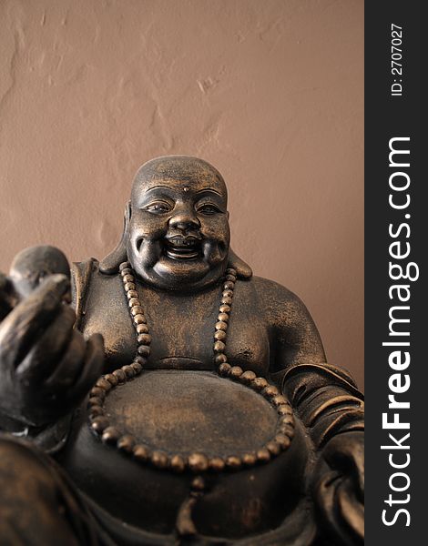 Bronze statue of budha with old wall in background