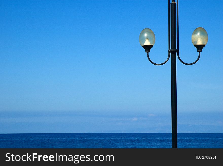 Lonely streetlamp against blue sea and sky