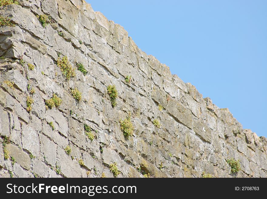 A solid castle rock wall against a blue sky. A solid castle rock wall against a blue sky