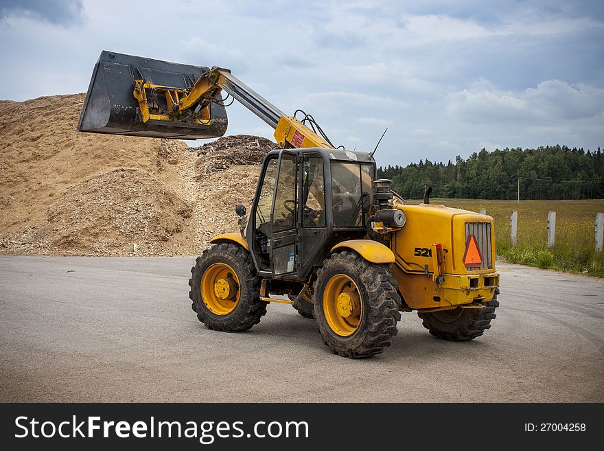 Yellow Telescopic Loader loading sawdust