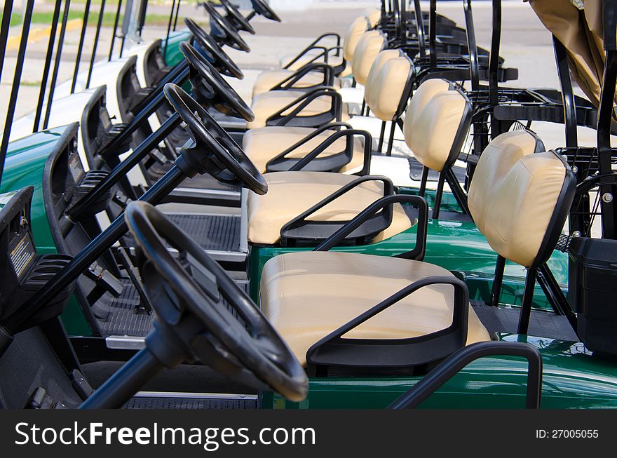 Row of golf carts closeup showing row of steering wheels and seats