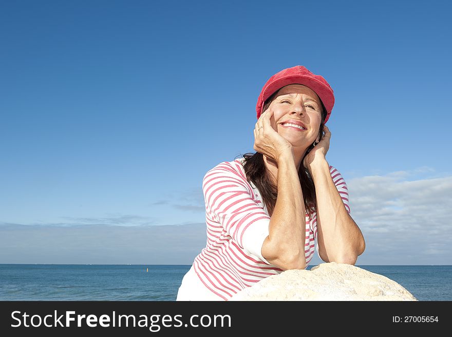 Portrait of relaxed and attractive looking senior woman enjoying active retirement and leisure time at sea, with ocean and blue sky as background and copy space. Portrait of relaxed and attractive looking senior woman enjoying active retirement and leisure time at sea, with ocean and blue sky as background and copy space.