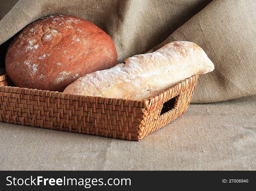 Nice wicker basket with rye and wheat bread on canvas background. Nice wicker basket with rye and wheat bread on canvas background