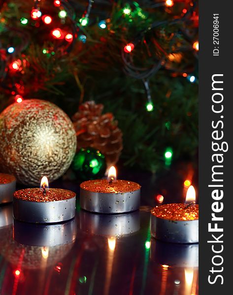 Few lighting candles on glass surfase with reflection on background with Christmas decorations. Few lighting candles on glass surfase with reflection on background with Christmas decorations