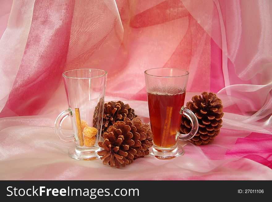 Hot Christmas drink with cinnamon on a pink background. Christmas decor with cones.