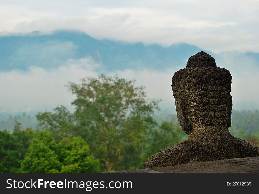 A Buddha statue on the Borobudur temple (Java, Indonesia) overlooking the landscape. A Buddha statue on the Borobudur temple (Java, Indonesia) overlooking the landscape.