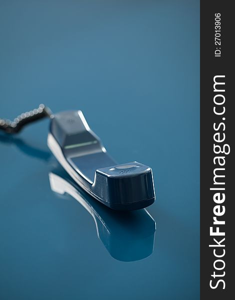 Old fashioned telephone receiver with reflection isolated on transparent blue background.