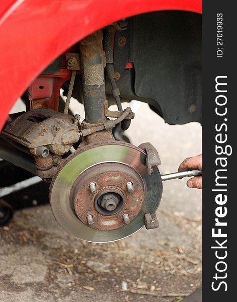 Mechanic removing brake pads from old disc brake.