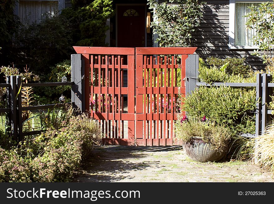 A unique red gate at the front yard of an old house.