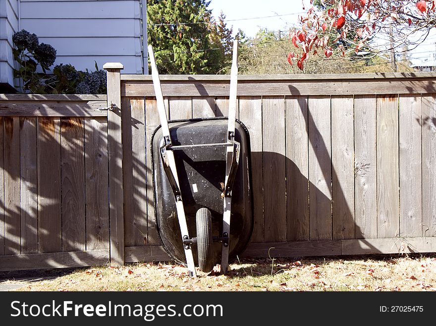 A wheelbarrow leaning on wooden fence