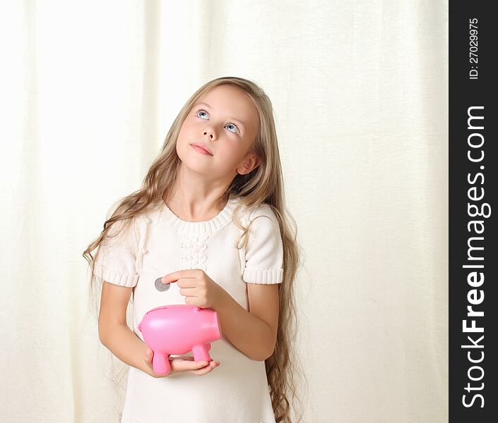 Little blond girl puts coin into piggy moneybox and dreaming about future purchase