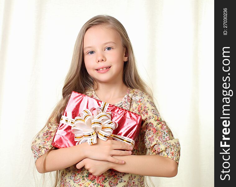 Little blond girl holding a red glamorous gift