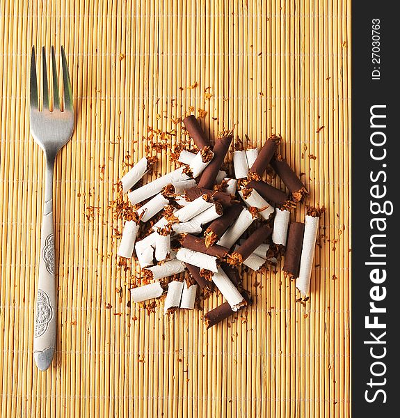 A concept for the harmful habit of smoking. Eating a meal composed of a pile of broken cigarettes. A concept for the harmful habit of smoking. Eating a meal composed of a pile of broken cigarettes