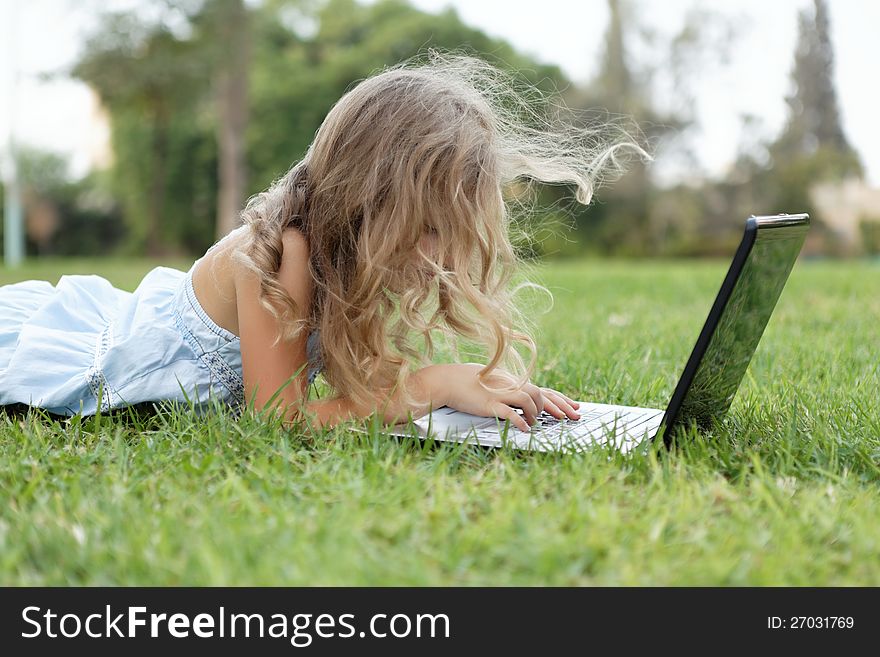 Blond baby girl with laptop outdoors