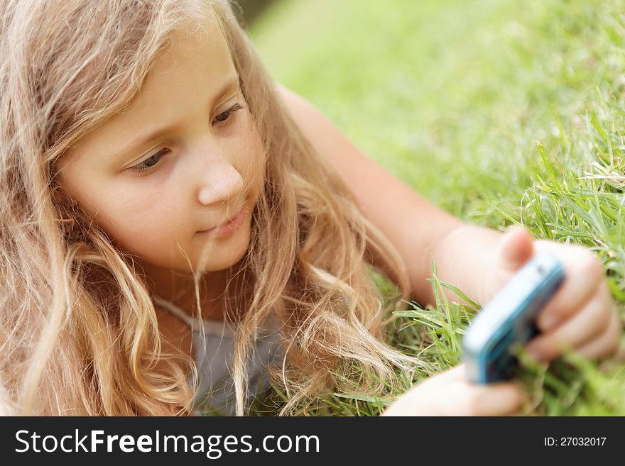 Pretty baby girl outdoors with a mobile phone