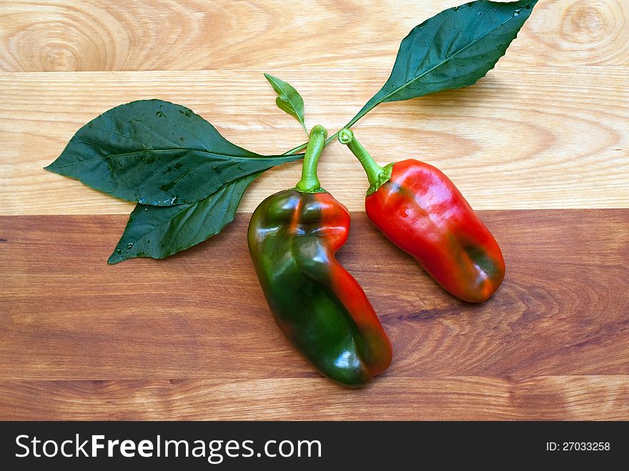 Two variegated sweet peppers (Red Roaster Hybrid) on wooden cutting board. Two variegated sweet peppers (Red Roaster Hybrid) on wooden cutting board.