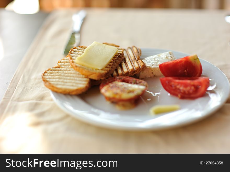 On a white plate crisp bread with cheese and tomatoes. On a white plate crisp bread with cheese and tomatoes