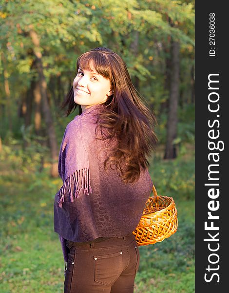 Beautiful woman walking in woodland looking back over her shoulder with her face caught in a beam of sunlight. Beautiful woman walking in woodland looking back over her shoulder with her face caught in a beam of sunlight