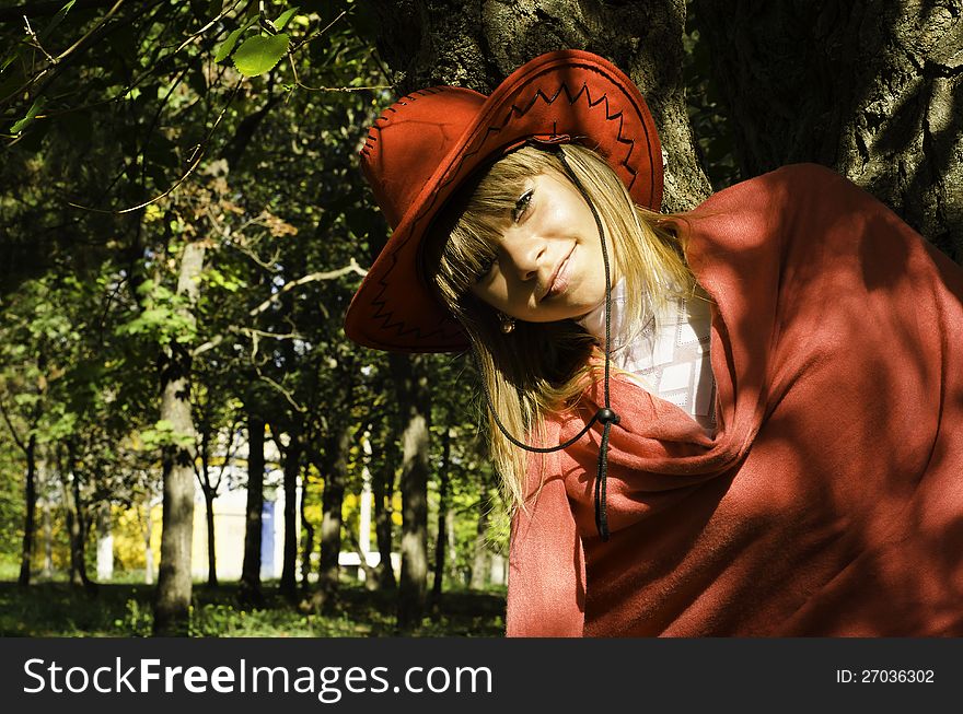 A beautiful girl in a red hat leaned against to the thick barrel of tree. A beautiful girl in a red hat leaned against to the thick barrel of tree.