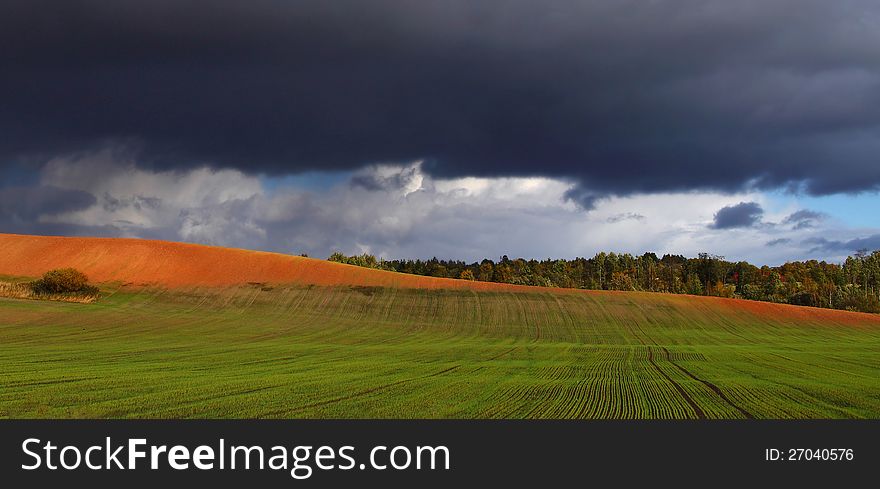 Green meadow and bright hill under dark cloudy sky. Green meadow and bright hill under dark cloudy sky