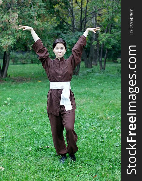 Zen pretty woman practicing exercise chi kung, tai chi, kung fu or yoga in natural park