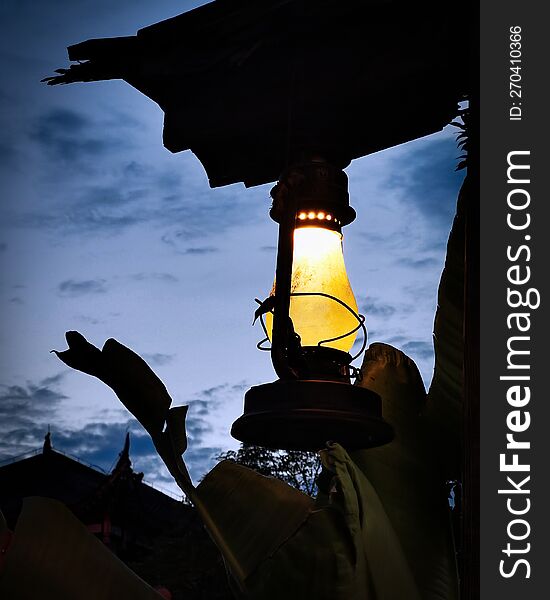 A lantern lit in front of the evening sky.