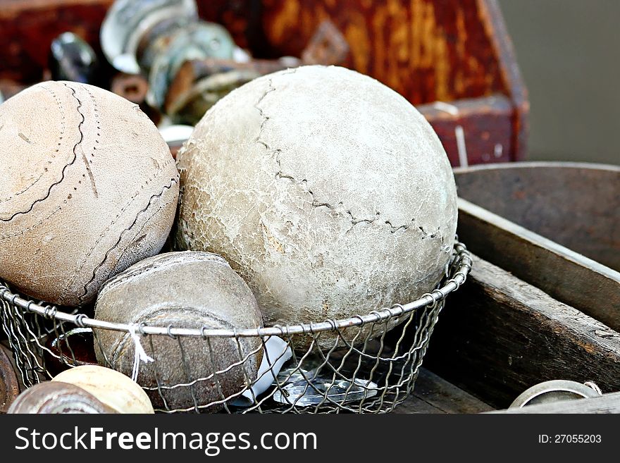 Vintage baseballs, and softballs in a wire basket.