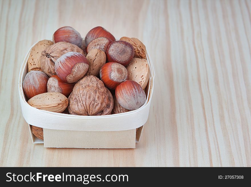 Basket with wood, walnuts and almonds. On a wooden texture.