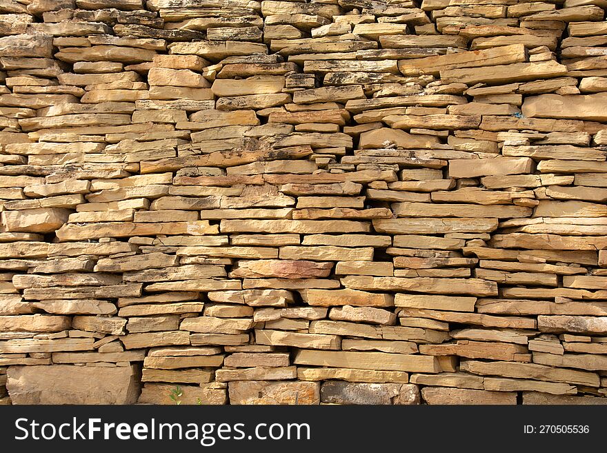 Regular stacked natural rock wall background picture, warm color.