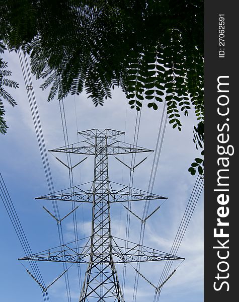 High voltage electricity pylon under the rear of the leaves in the midst of the clouds the sky. High voltage electricity pylon under the rear of the leaves in the midst of the clouds the sky.