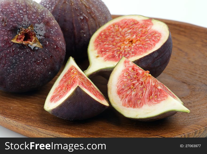 Perfect Ripe Figs Full Body and Slices with Droplets closeup on Wooden Plate. Perfect Ripe Figs Full Body and Slices with Droplets closeup on Wooden Plate