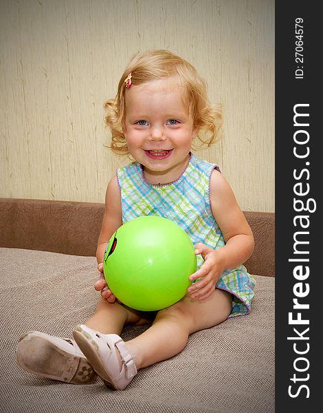 The little blond smiling baby girl with ball