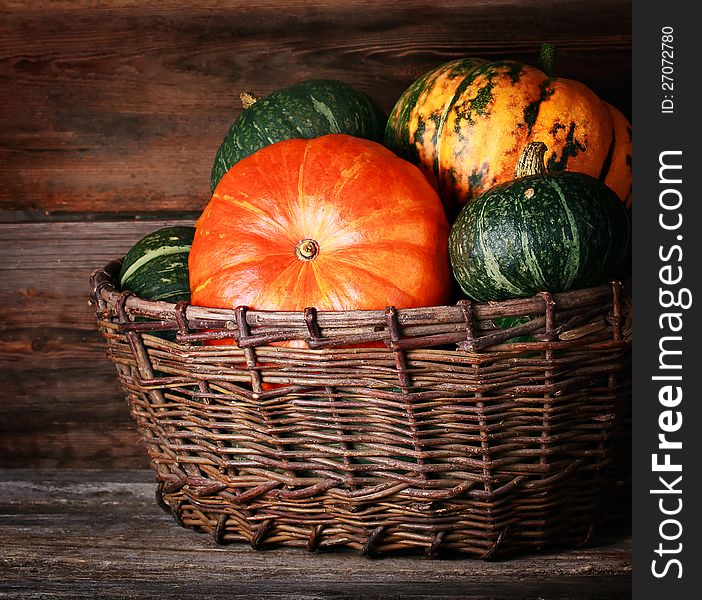 Harvested pumpkins in  basket  over wooden surface