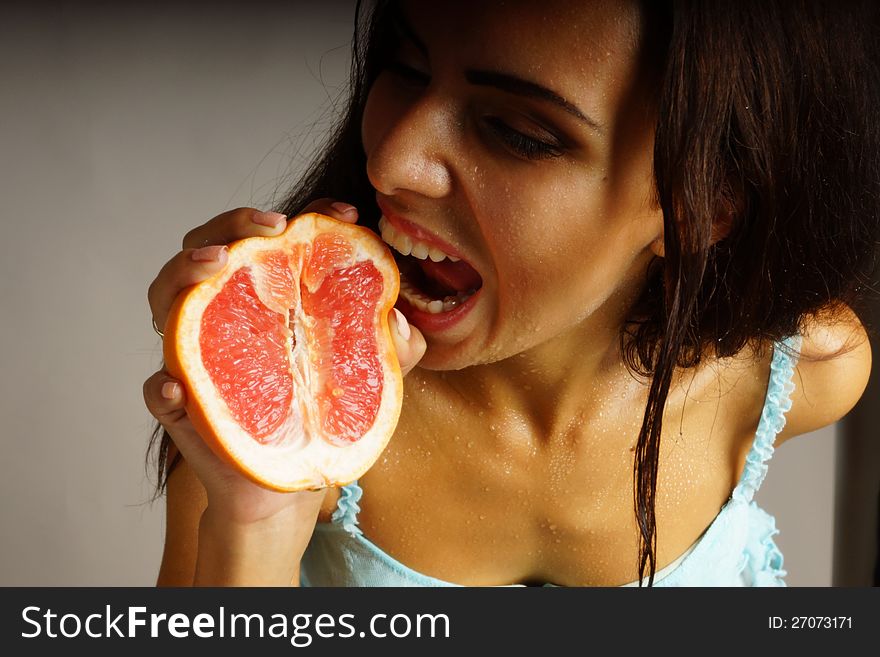 The girl in the hands holding grapefruit on a dark background. The girl in the hands holding grapefruit on a dark background.