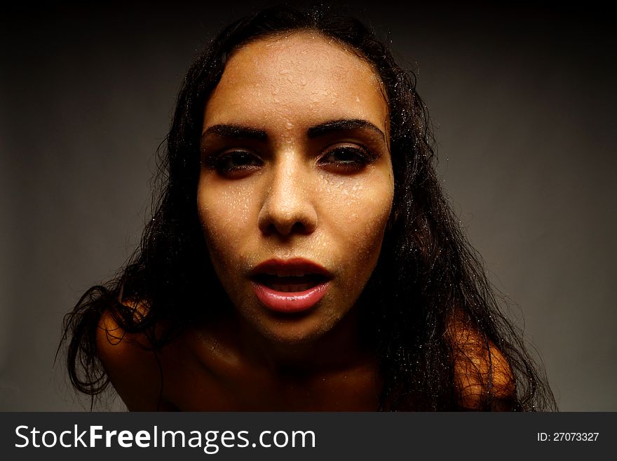 Portrait of a girl on a dark background. Water on her face.