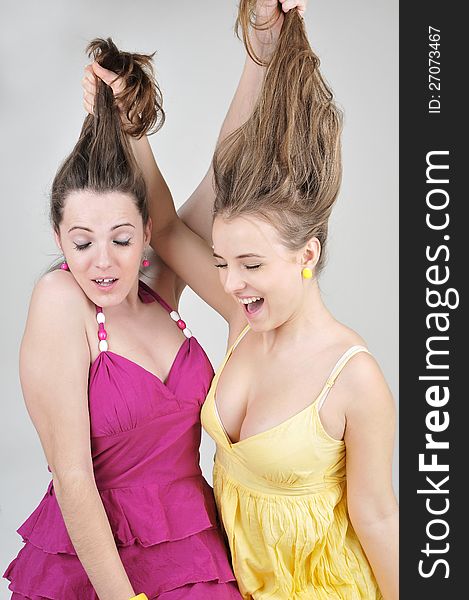 Two funny  girl friends pull each other s hair.