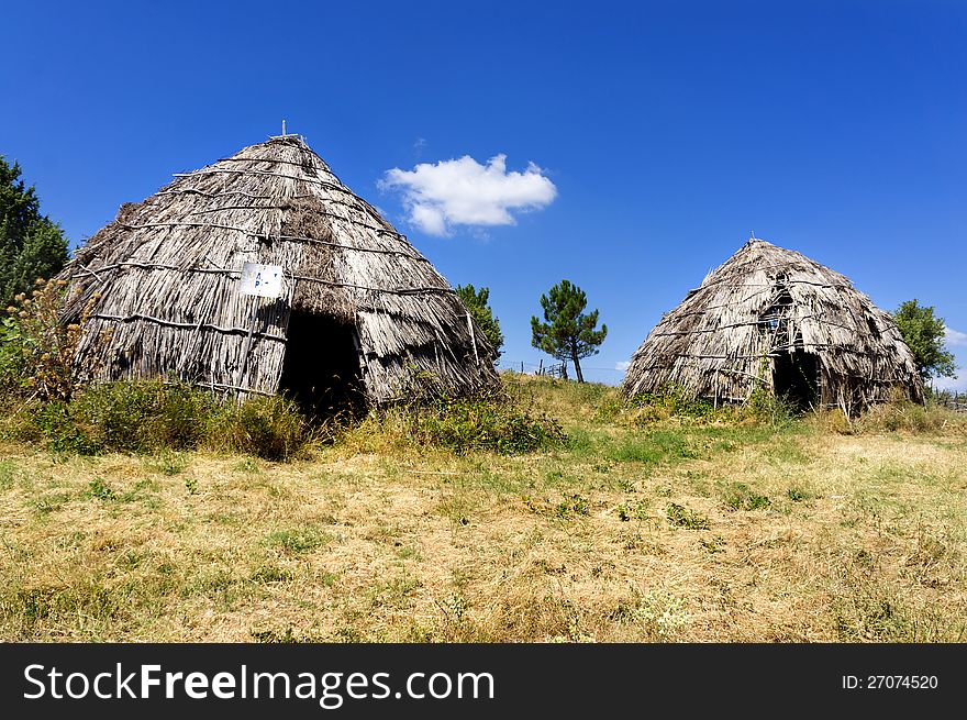 Two traditional straw huts in greek country, on a sunny day