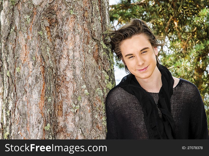 Portrait of a teenager boy leaning against a tree. Portrait of a teenager boy leaning against a tree.