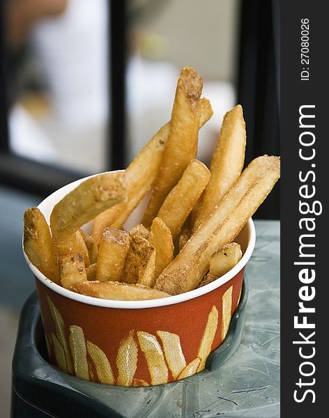 A cup of French Fries waits to be eaten at a baseball game. A cup of French Fries waits to be eaten at a baseball game.
