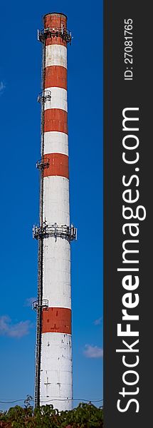 Industrial brick chimney with cellular equipment against blue sky