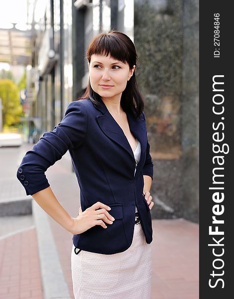 Business woman standing with hand on his belt against a background of business centers