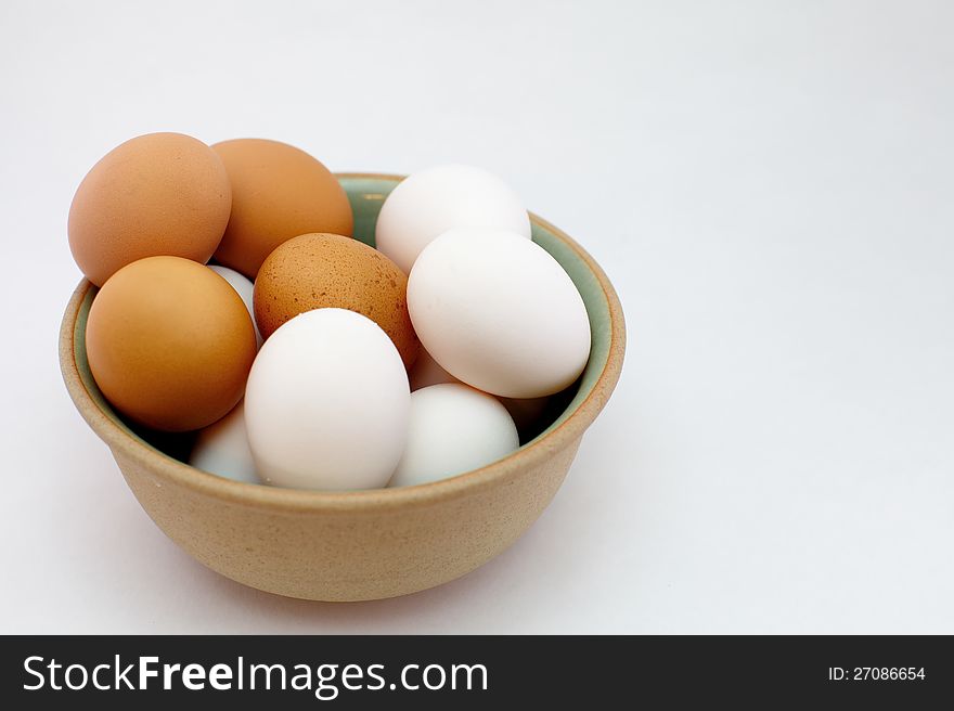 White and brown eggs in bowl on white background