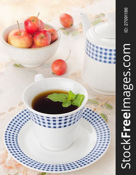 A cup of tea with mint and apples in the background on the table. A cup of tea with mint and apples in the background on the table