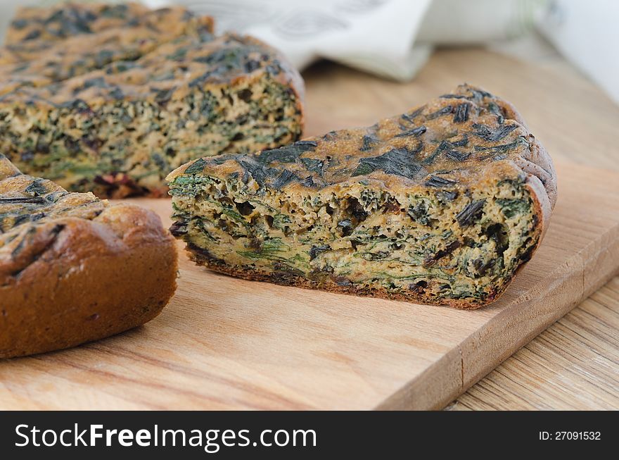 Piece of cake with fresh herbs and spinach on a wooden board closeup. Piece of cake with fresh herbs and spinach on a wooden board closeup