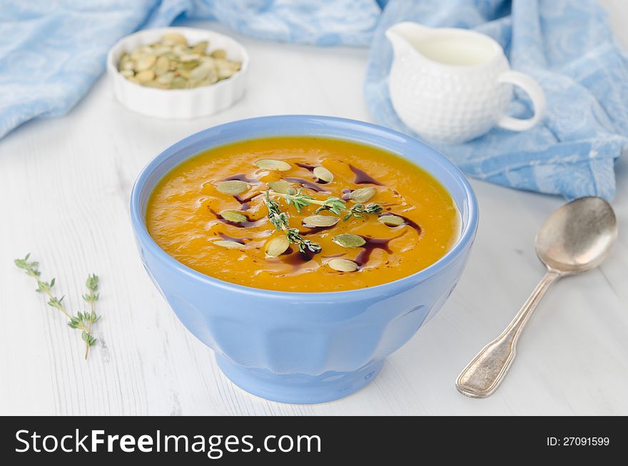 Pumpkin soup with pumpkin seeds and oil in a blue ceramic bowl, close-up horizontal. Pumpkin soup with pumpkin seeds and oil in a blue ceramic bowl, close-up horizontal