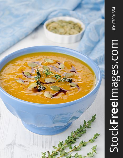 Pumpkin soup with pumpkin seeds and oil in a blue ceramic bowl, close-up. Pumpkin soup with pumpkin seeds and oil in a blue ceramic bowl, close-up